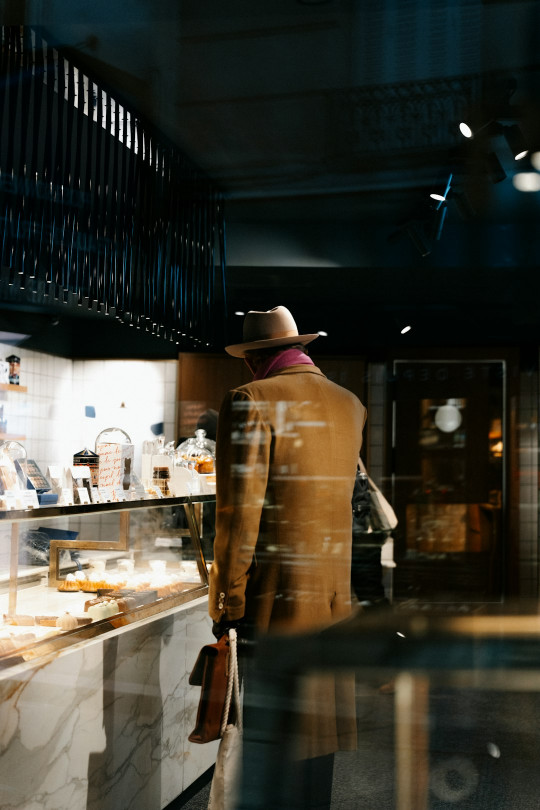 A man in a suit and hat standing in front of a counter