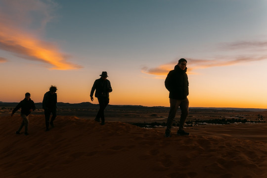 A group of people standing on top of a sandy beach