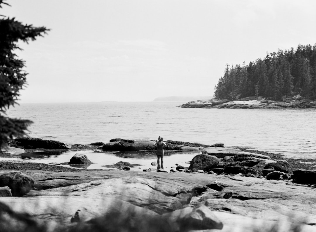 A black and white photo of a person standing on a beach