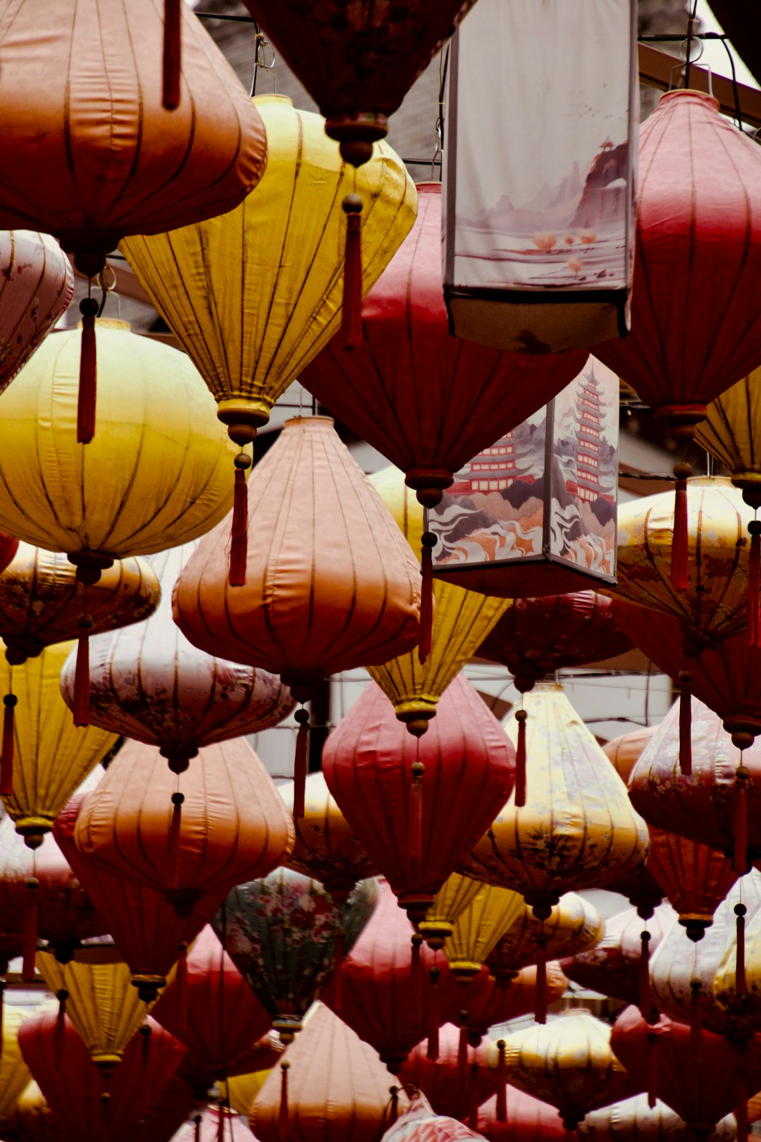 A bunch of red and yellow lanterns hanging from the ceiling