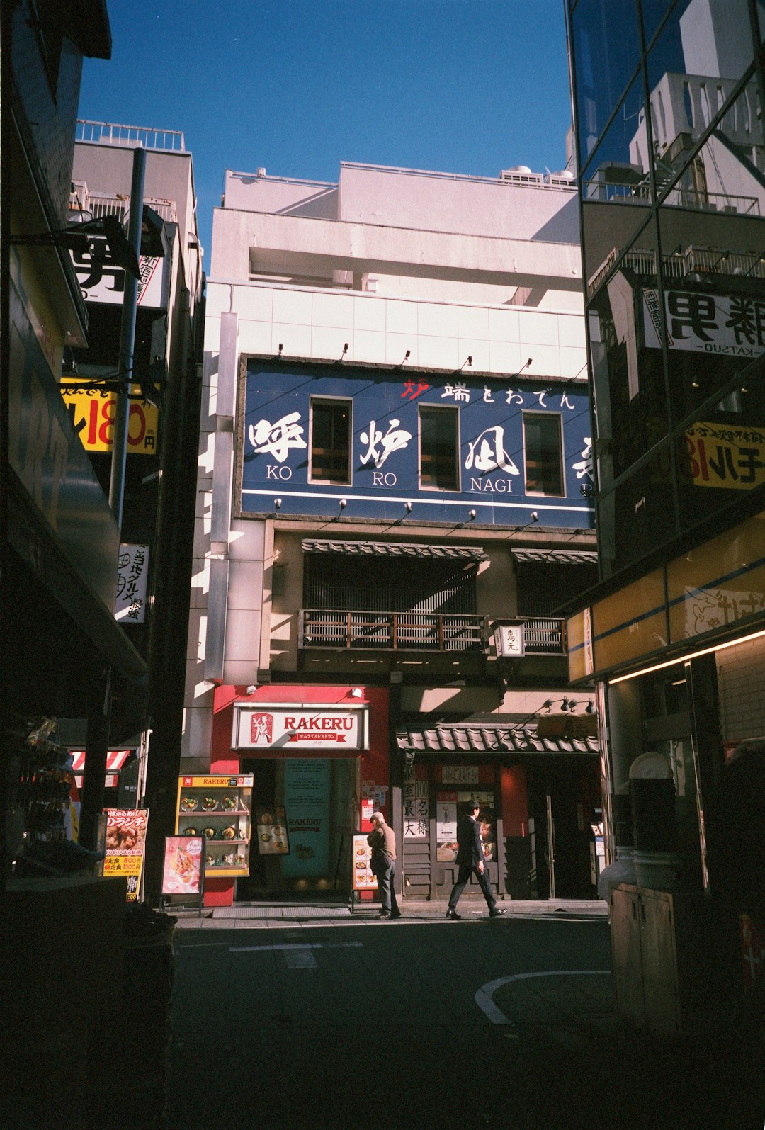 A city street with buildings and people walking on the sidewalk