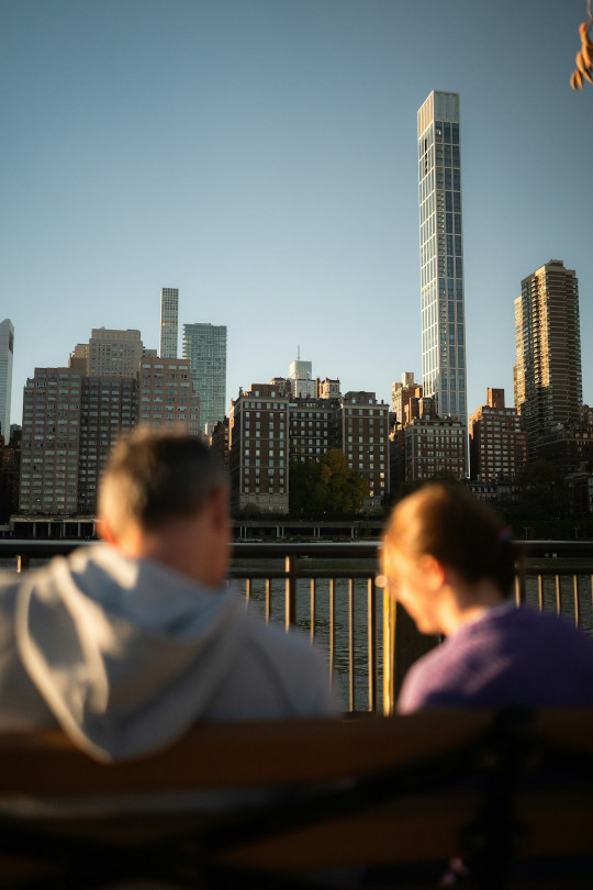 Two people sitting on a bench in front of a city skyline